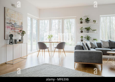 Des tulipes en vase en céramique placés sur une table en bois avec deux chaises gris debout dans le coin du salon lumineux intérieur avec des décorations sur c Banque D'Images