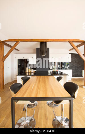 Tabourets De Bar en bois à table dans une spacieuse cuisine intérieur avec des meubles blancs et de comptoir noir Banque D'Images