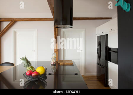 Fruits sur noir brillant sur le comptoir de cuisine île dans l'intérieur de la chambre avec portes blanches Banque D'Images