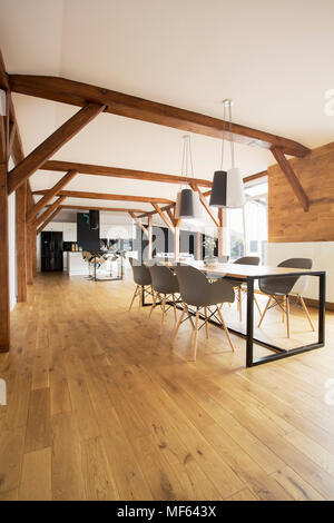 Table à manger en bois au-dessus des lampes et des chaises dans un espace libre intérieur avec cuisine dans l'arrière-plan Banque D'Images