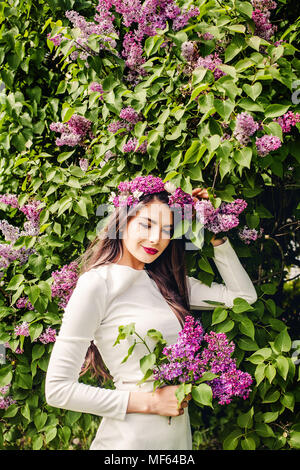 Jeune mannequin avec des fleurs lilas dans sa main à l'extérieur du parc. Beautiful woman portrait Banque D'Images