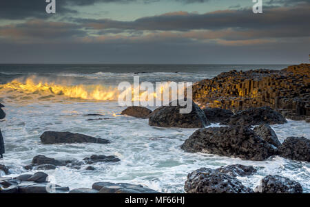 Les vagues se briser sur la formation rock hexagonal à la Giant Causeway juste avant le coucher du soleil, l'Irlande du Nord, Royaume-Uni Banque D'Images