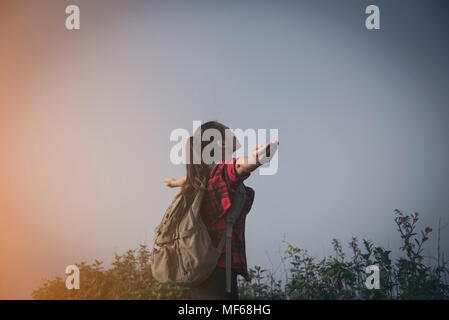 Jeune fille Hipster avec sac à dos, appréciant le coucher du soleil sur le pic de Foggy Mountain. Hôtels touristiques sur maquette vue d'arrière-plan. À la lumière du soleil voyage en randonneur Banque D'Images