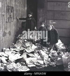 1972, photo historique montrant trois petits enfants debout ensemble sur un tas de déchets ménagers à l'extérieur où ils vivent et jouent dans le sud de Londres. Dans les années 1970, un travailleur du secteur public, les grèves sont une caractéristique commune de la vie et refuser était l'une des choses qui ne sont pas recueillies pour les semaines menant à de graves problèmes de santé publique et de l'environnement et pour les enfants danger lorsqu'ils jouent à l'extérieur. Banque D'Images