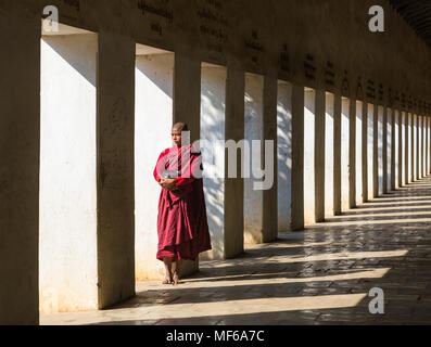 Moine Bouddhiste Novice debout dans l'Est de l'escalier, la pagode de Shwezigon Bagan Nyaung U,, Myanmar (Birmanie), l'Asie en février - les colonnes et les ombres Banque D'Images
