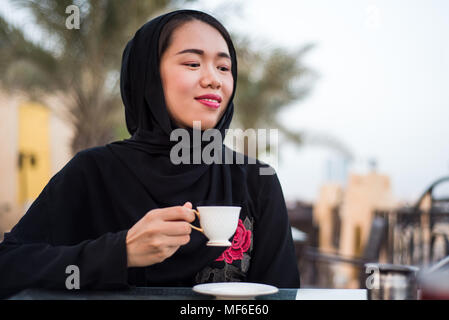 Femme musulmane ayant une tasse de café dans un bar en plein air Banque D'Images