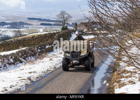 Un agriculteur sur un quad en hiver la neige sur les Pennines près de Alston, Cumbria UK Banque D'Images