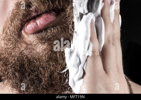 Un jeune homme en mousse à raser, la préparation pour retirer les cheveux, partie d'un visage close-up Banque D'Images