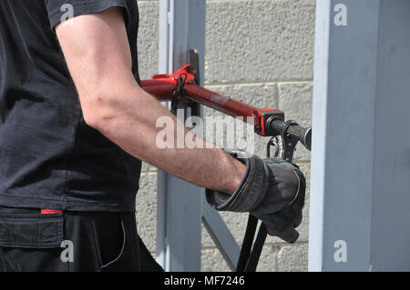 Fire fighter utilise les outils hydrauliques à enfreindre une porte verrouillée Banque D'Images