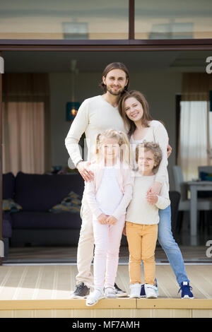 Les parents et les enfants à la caméra au comité permanent sur la terrasse de la chambre Banque D'Images