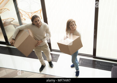 Young couple holding moving boxes entrant dans maison neuve, frais généraux v Banque D'Images