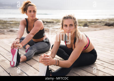 Les jeunes femmes sportives exerçant sur une journée ensoleillée en faisant des étirements et renforcement de la jambe Banque D'Images