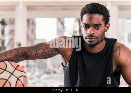 Portrait of man with tattoos holding basketball Banque D'Images