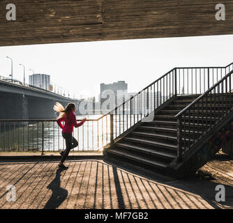 Jeune femme en courant vers les escaliers à une rivière Banque D'Images