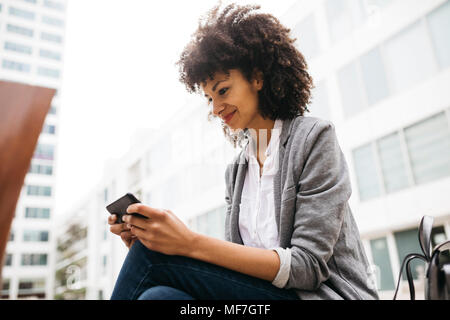 Smiling woman using cell phone outdoors Banque D'Images