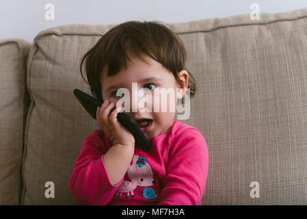 Baby Girl talking on mobile phone at home Banque D'Images