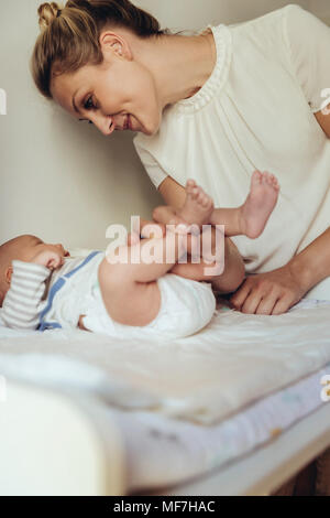 Mother smiling at bébé nouveau-né sur une table à langer Banque D'Images