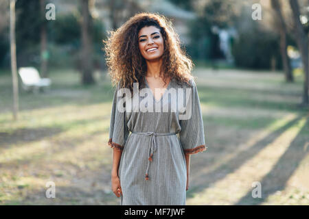 Espagne, Andalousie, Grenade. Happy young woman with curly hairstyle dans un parc urbain. Concept de vie. Banque D'Images