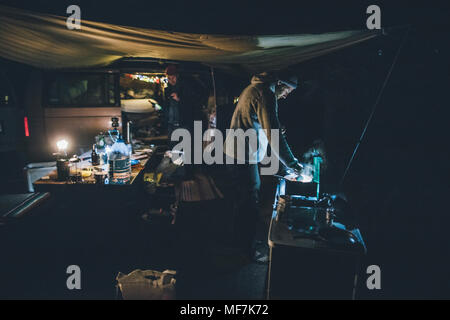 Le Canada, la Colombie-Britannique, deux hommes la cuisson sous bâche à minibus de nuit Banque D'Images