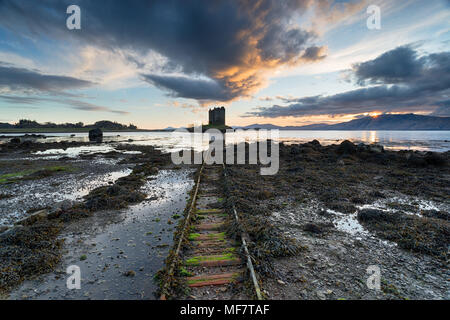 Ciel coucher de soleil spectaculaire sur les ruines du château de Stalker sur les rives du Loch Linnhe près de Appin à Argyll en Ecosse Banque D'Images