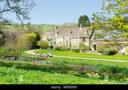 La rivière qui traverse l'Œil le joli village de Cotswold abattage supérieur dans le Gloucestershire, Royaume-Uni, avec un groupe de personnes ayant un pique-nique sur la rive Banque D'Images
