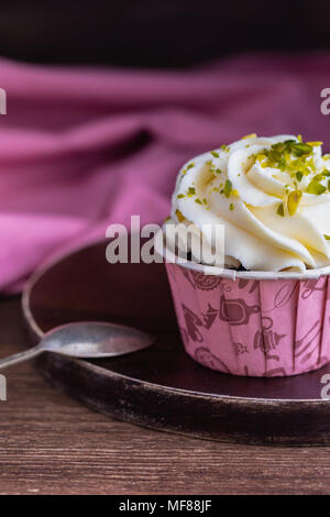 Muffins au chocolat maison ou des petits gâteaux à la vanille et crème à la pistache sur le fond en bois, teinté Banque D'Images