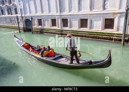 Venise, Italie - 28 Février 2015 : un gondolier steers un couple vers le bas d'un canal à Venise, Italie sur une journée d'hiver ensoleillée. Banque D'Images