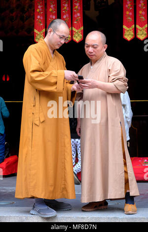 Deux moines bouddhistes avec un téléphone mobile, Temple du Bouddha de Jade, Shanghai, Chine Banque D'Images