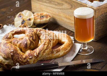 Bretzel fait maison avec du sel de mer et verre de bière sur la table en bois rustique Banque D'Images