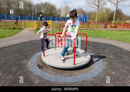 Frères jouant sur une balançoire dans un aire de jeux pour enfants dans le village de tonne près de Wolverhampton. Banque D'Images