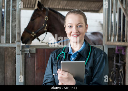 Portrait of Female Vet With Digital Tablet examinant l'Dans Stable Banque D'Images
