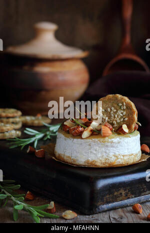 Fromage cuit au four avec des amandes, le romarin, le miel et les biscuits sur un plateau de métal Banque D'Images