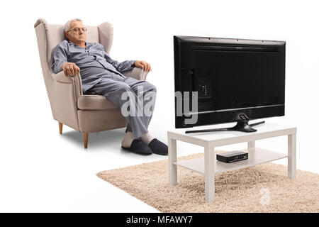 Grumpy young en pyjama assis dans un fauteuil et regarder la télévision isolé sur fond blanc Banque D'Images
