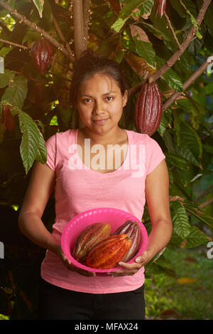 Farmer young girl holding gousses de cacao colorés sur fond d'arbres Banque D'Images