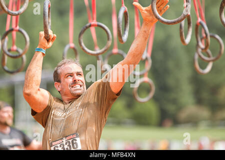 Un homme comme il pivote de grimaces suspendu de bagues en bois apparentes à la robuste Maniac Parcours event le 22 août 2015 à Conyers, GA. Banque D'Images