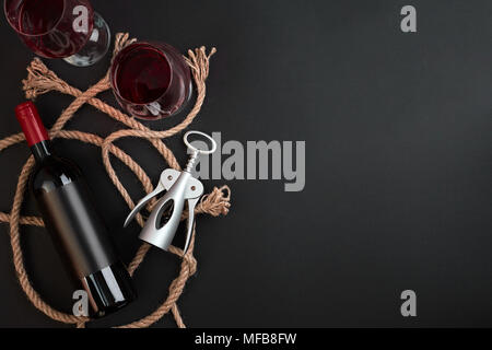 Bouteille de vin rouge, deux verres et corkscrew sur fond noir. Top View with copy space Banque D'Images