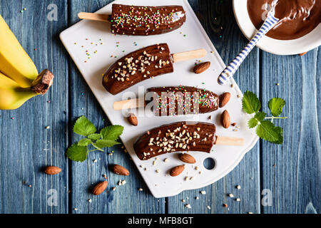 Les bananes enrobée de chocolat et saupoudrée d'amandes hachées et sprinkles colorés Banque D'Images