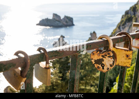 Serrure en forme de coeur jaune rouillé sur une clôture métallique en vue d'une des petites îles de Corfou, Grèce Banque D'Images