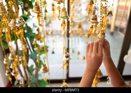 Les mains des filles sont liés à l'or des cloches de la foi bouddhiste. Les croyances, les Thaïlandais s'écrit sur la lettre des cloches, aura de la chance. Temple thaï, Sel Banque D'Images