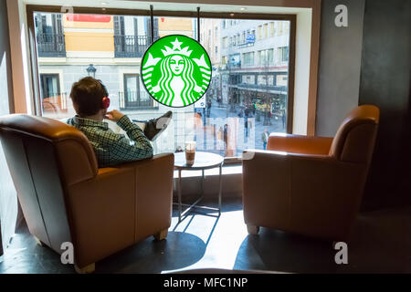 Madrid, Espagne - le 9 mars 2015 : un utilisateur lit un livre et écoute de la musique tout en étant assis à une fenêtre dans un café Starbucks dans le centre de Madrid, sur Banque D'Images