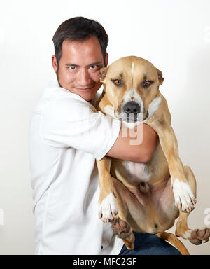 Young Adult man smiling while holding un chien de taille moyenne à grande dans ses bras isolated on white Banque D'Images