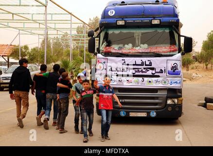 Damas, Syrie. Apr 25, 2018. Les enfants sont vus près de la distribution de l'aide d'un bus dans l'Dweir abri dans la campagne de la capitale, Damas, Syrie, le 25 avril 2018. L'abri Dweir contient un grand nombre de familles qui ont fui les villes tenues par les rebelles, anciennement de l'Est de Ghouta campagne de Damas. Credit : Ammar Safarjalani/Xinhua/Alamy Live News Banque D'Images