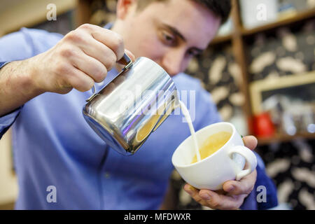 Photo de barista man pouring lait en tasse de café Banque D'Images