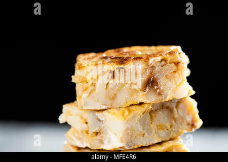 Libre de quelques morceaux de Tortilla de Patatas typique, l'omelette espagnole, sur une table en bois rustique, d'un fond noir Banque D'Images