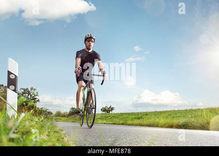 Un cycliste sur route ensoleillée Banque D'Images