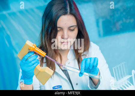 Jeune femme technicien utilise une pipette dans un laboratoire chimique Banque D'Images