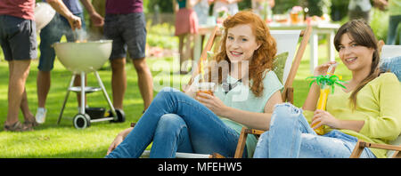 Les filles avec des boissons chilling sur les chaises longues dans la campagne Banque D'Images