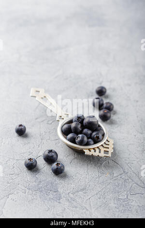 Les bleuets ou myrtilles dans une antique passoire du thé sur fond gris. La saine alimentation et nutrition concept. De délicieux fruits bio frais juteux. Banque D'Images