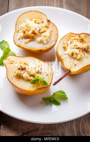 Les poires gratiné au fromage ricotta, noix, miel et cannelle sur fond de bois rustique Banque D'Images
