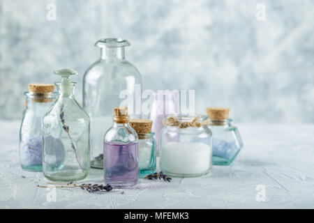 Bouteilles et pots en verre avec des huiles aromatiques et de sel et sur fond clair Banque D'Images